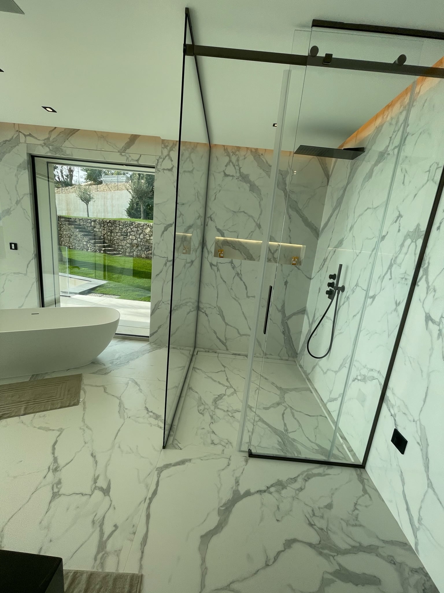 Rénovation douche italienne Menton - Paroi vitrée noire, marbre blanc Calacatta, baignoire îlot design
